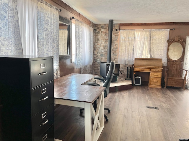 home office with a wood stove, a textured ceiling, and wood-type flooring