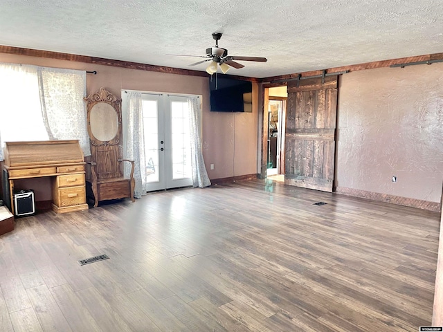 unfurnished living room with ceiling fan, wood-type flooring, french doors, and a textured ceiling