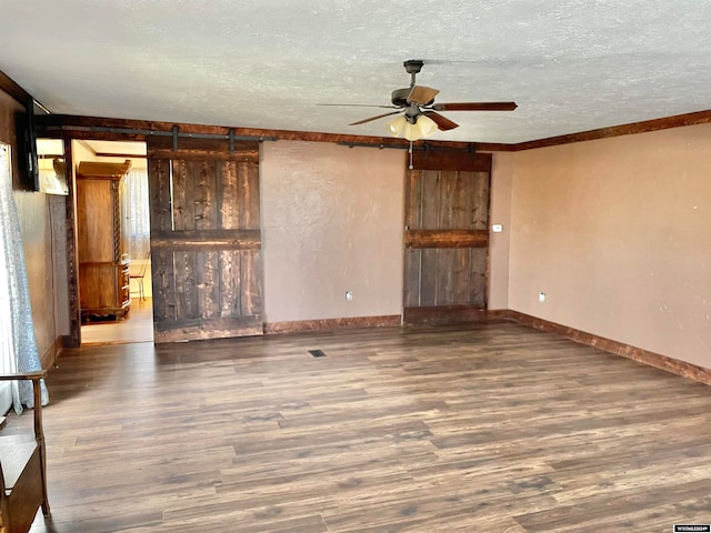 unfurnished living room with ceiling fan, a textured ceiling, a barn door, and wood-type flooring