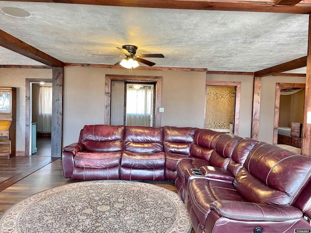 living room with ceiling fan, wood-type flooring, a textured ceiling, and beamed ceiling