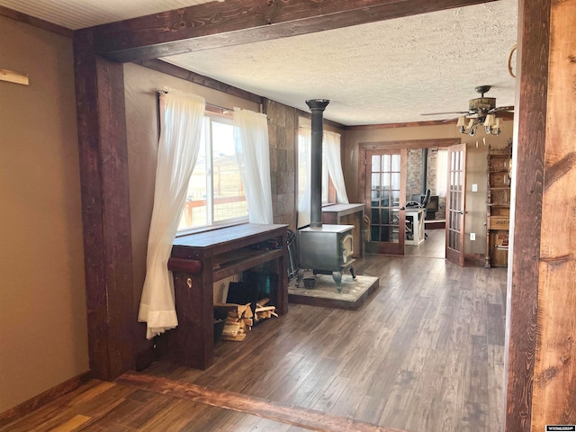 misc room featuring ceiling fan, dark wood-type flooring, a textured ceiling, and a wood stove