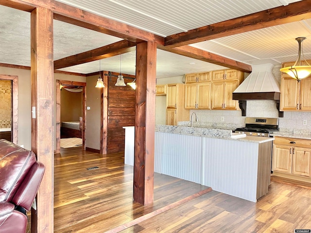 kitchen with beamed ceiling, custom range hood, stainless steel range with gas stovetop, and light brown cabinetry