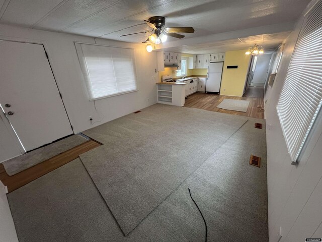 309 S Cherry, Pavillion, WY 82523 - unfurnished living room with ceiling fan with notable chandelier and light wood-type flooring