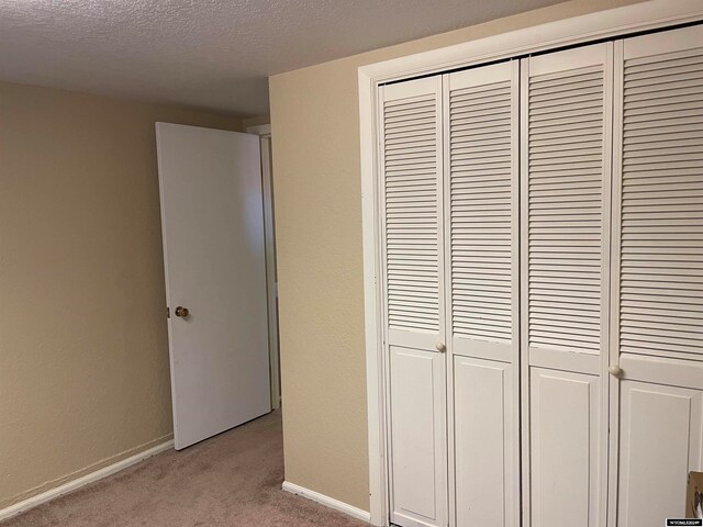 interior space featuring a textured ceiling and light colored carpet