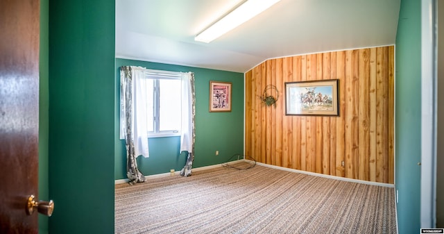 interior space featuring wood walls, carpet, and lofted ceiling