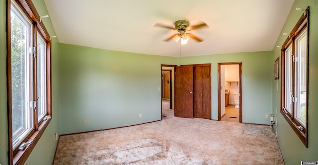 unfurnished bedroom with ceiling fan, connected bathroom, light colored carpet, and multiple windows