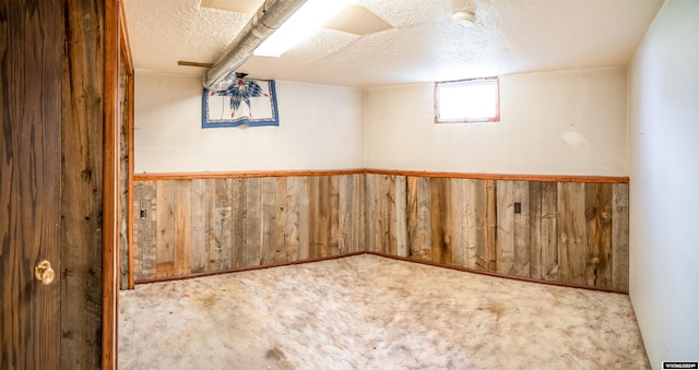 basement featuring wood walls, a textured ceiling, and carpet flooring