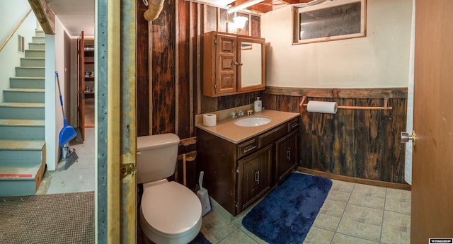 bathroom featuring tile patterned floors, vanity, wood walls, and toilet