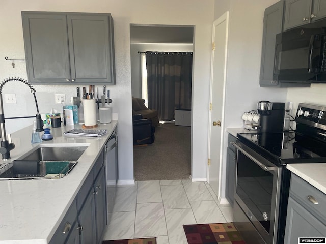 kitchen with light colored carpet, appliances with stainless steel finishes, sink, and gray cabinetry