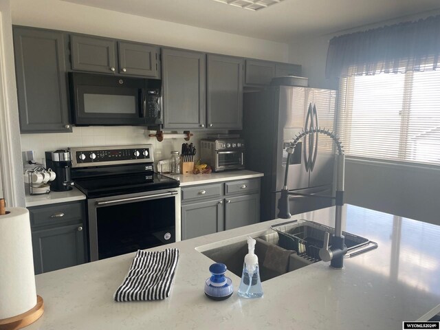 kitchen with gray cabinetry, a breakfast bar area, sink, and stainless steel appliances