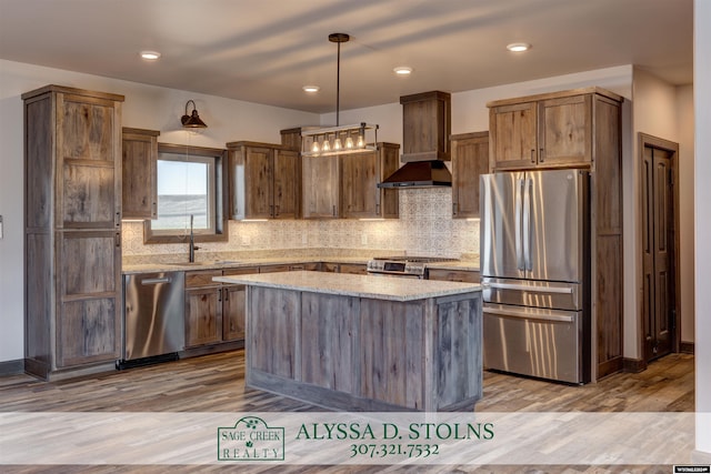 kitchen with stainless steel appliances, wood finished floors, a sink, light stone countertops, and custom range hood