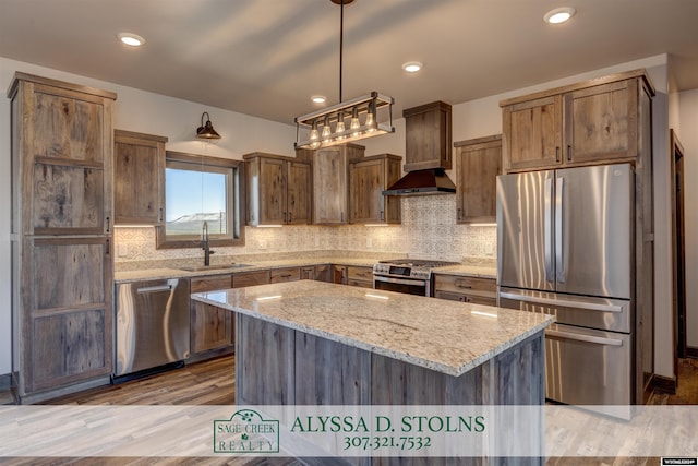 kitchen featuring appliances with stainless steel finishes, a center island, a sink, light stone countertops, and backsplash