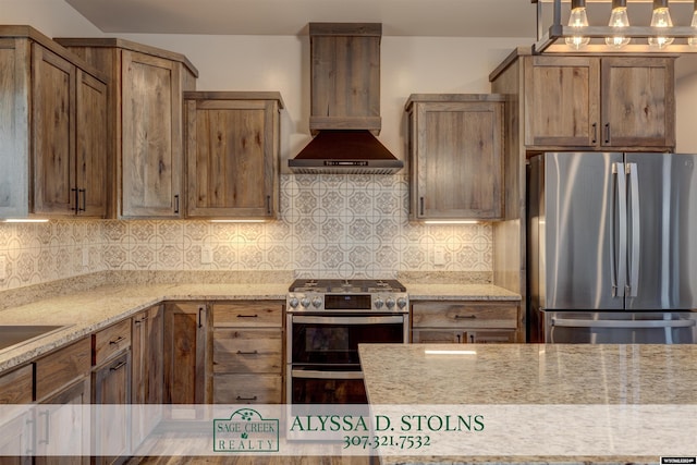 kitchen with light stone counters, pendant lighting, stainless steel appliances, decorative backsplash, and wall chimney exhaust hood