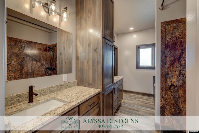 bathroom with recessed lighting, wood finished floors, vanity, baseboards, and a shower