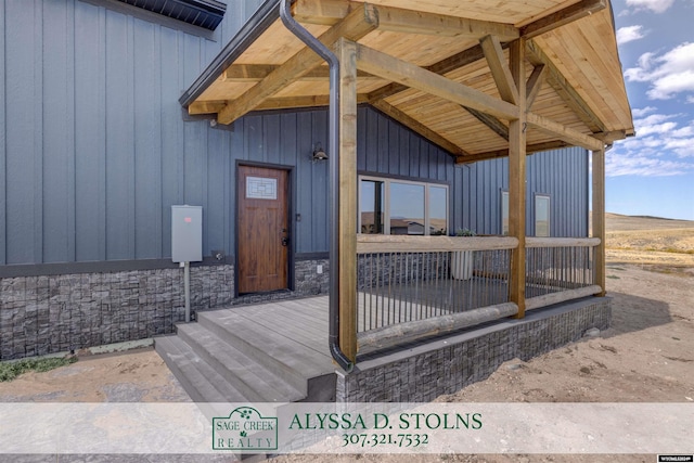 view of exterior entry with stone siding and board and batten siding