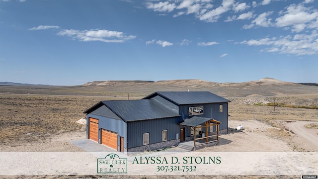 view of front of property featuring an outbuilding, metal roof, a mountain view, a detached garage, and an outdoor structure