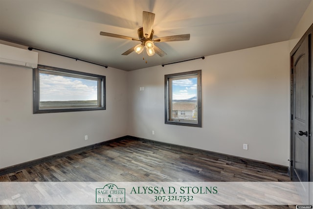 spare room with ceiling fan, dark wood-type flooring, a wall unit AC, and baseboards