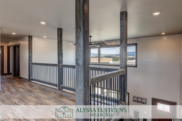 hall with recessed lighting, wood finished floors, and an upstairs landing