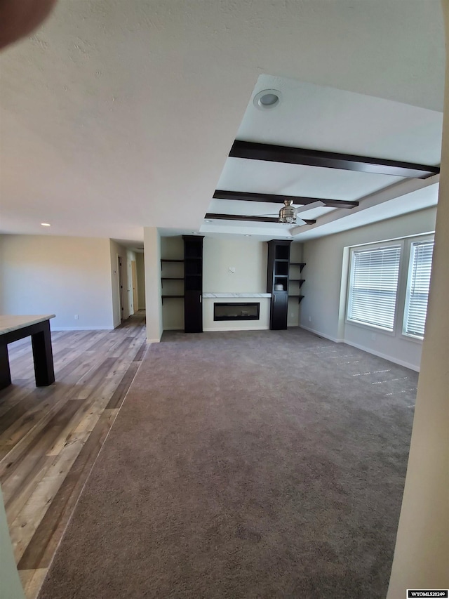 unfurnished living room with ceiling fan, hardwood / wood-style floors, and beamed ceiling