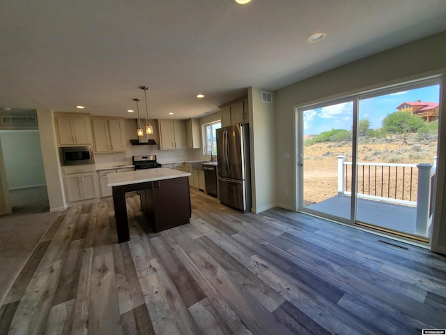 kitchen featuring stainless steel appliances, pendant lighting, and wood-type flooring