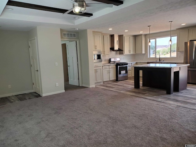 kitchen with ceiling fan, a kitchen island, wall chimney exhaust hood, carpet, and stainless steel appliances