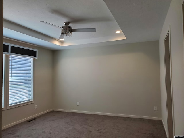 carpeted empty room featuring ceiling fan and a tray ceiling