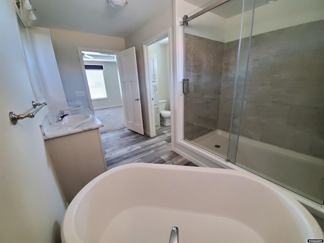 full bathroom with hardwood / wood-style floors, separate shower and tub, toilet, and vanity