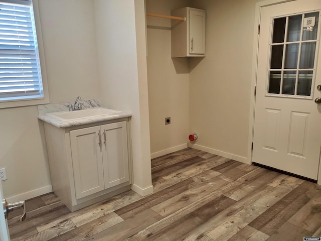 washroom featuring sink, electric dryer hookup, cabinets, and light wood-type flooring