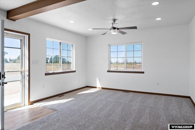 spare room featuring a wealth of natural light, carpet floors, ceiling fan, and a textured ceiling