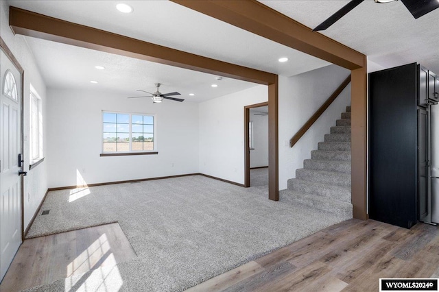 interior space featuring beam ceiling, ceiling fan, and light carpet