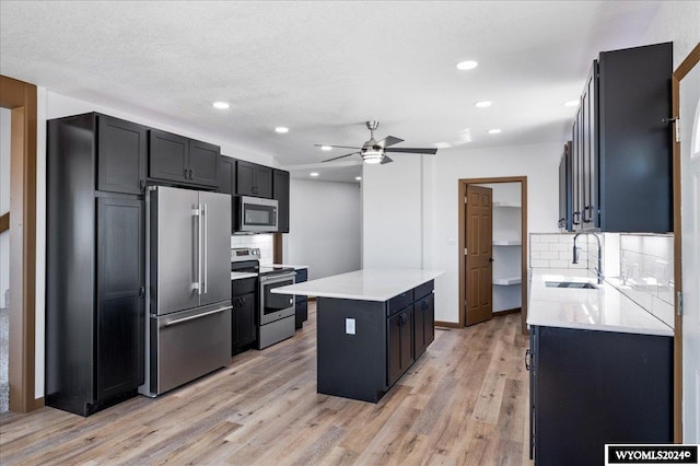 kitchen featuring light wood-type flooring, appliances with stainless steel finishes, sink, and ceiling fan