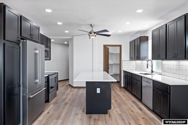 kitchen with stainless steel appliances, ceiling fan, a center island, and light hardwood / wood-style flooring