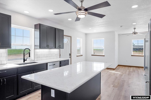 kitchen featuring sink, tasteful backsplash, a kitchen island, and a healthy amount of sunlight