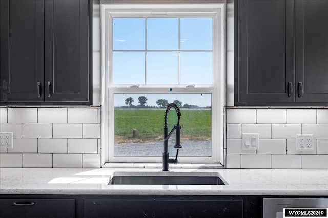 kitchen featuring backsplash, sink, plenty of natural light, and light stone counters