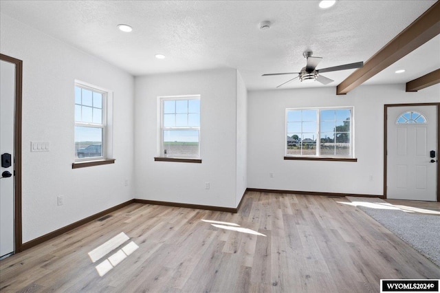 interior space featuring beamed ceiling, light hardwood / wood-style flooring, ceiling fan, and a textured ceiling