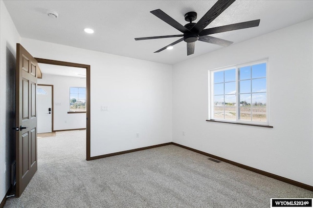 spare room featuring ceiling fan and light carpet