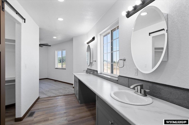 bathroom featuring ceiling fan, dual vanity, and hardwood / wood-style flooring