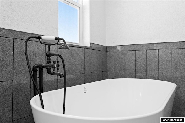 bathroom featuring a washtub and tile walls