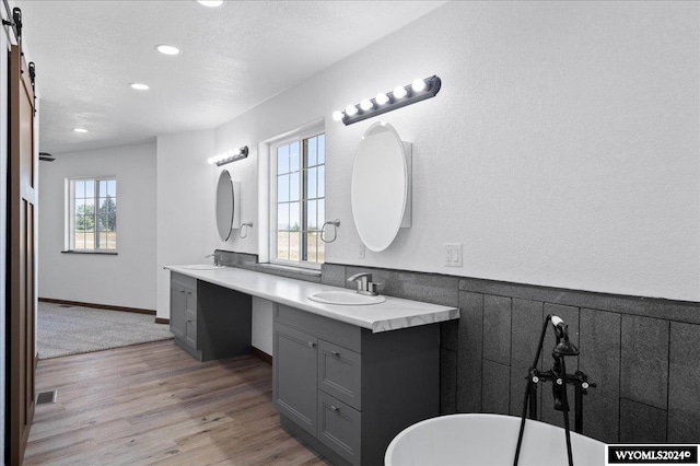 bathroom with a washtub, hardwood / wood-style flooring, and double vanity