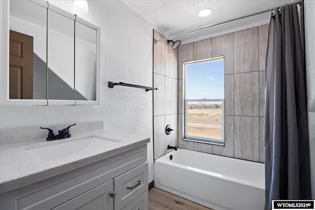 bathroom featuring hardwood / wood-style flooring, shower / tub combo with curtain, vanity, and a textured ceiling