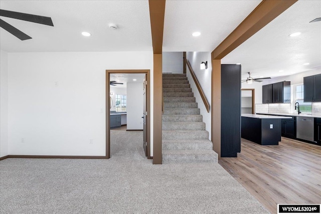 unfurnished living room with ceiling fan, sink, and light hardwood / wood-style flooring