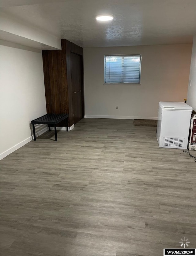 basement with light wood-type flooring and refrigerator