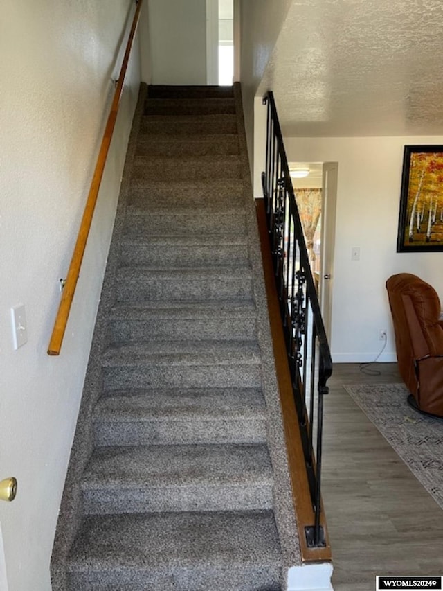 stairway with a textured ceiling and hardwood / wood-style flooring