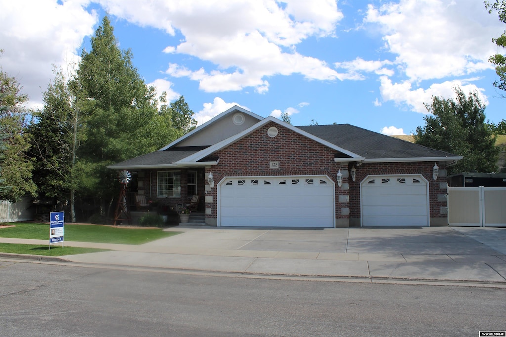 view of front of property with a garage, roof with shingles, concrete driveway, and brick siding