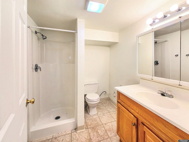 bathroom featuring a stall shower, baseboards, vanity, and toilet