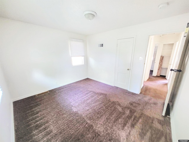 empty room featuring carpet, visible vents, and baseboards