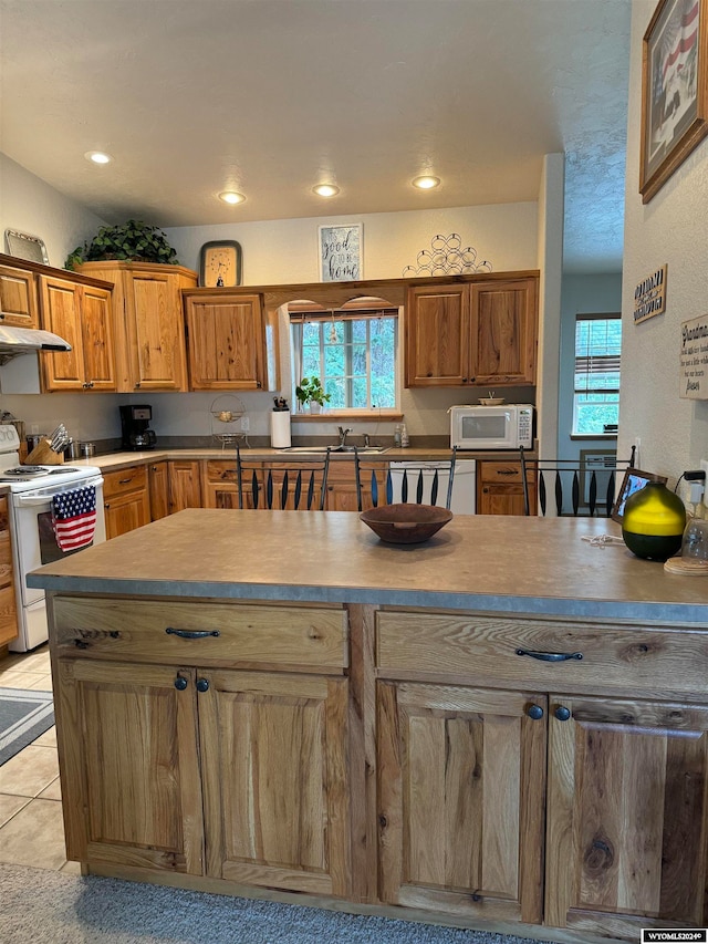 kitchen featuring sink, white appliances, a healthy amount of sunlight, and light tile patterned floors