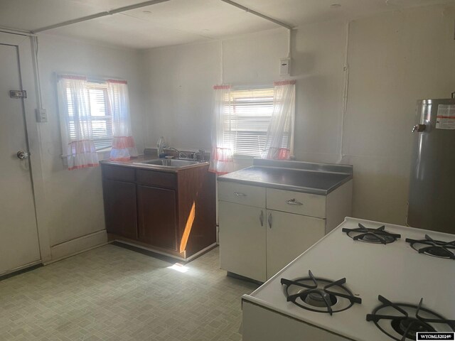 kitchen with white cabinetry, range, sink, water heater, and light tile patterned flooring