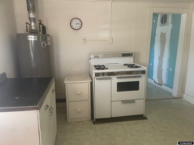 kitchen featuring light tile patterned flooring, gas range gas stove, water heater, and white cabinetry