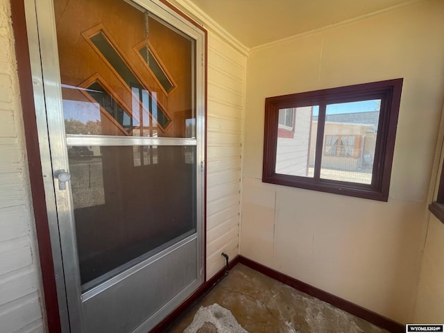 entryway featuring concrete flooring, ornamental molding, and baseboards